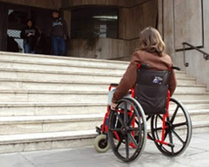 Noia amb cadira de rodes davant unes escales